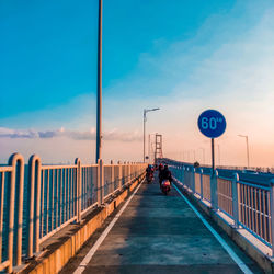 Road sign on bridge against sky