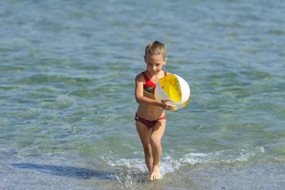 Full length of girl holding ball on beach