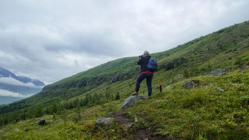 Full length rear view of senior woman against mountains taking photos