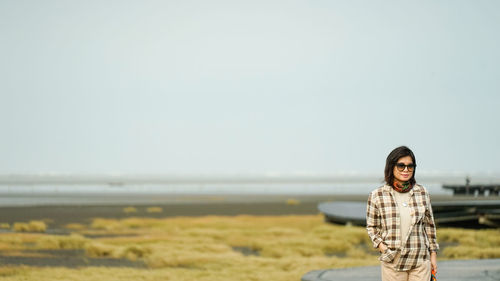 Portrait of smiling woman standing on land against clear sky