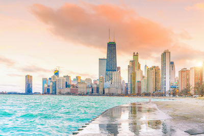 Modern buildings by swimming pool against sky during sunset