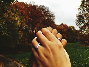 Close-up of hand holding plant against trees