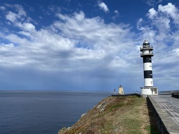 Lighthouse by sea against sky