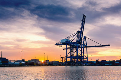 Cranes against sky during sunset