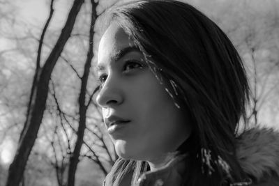 Low angle view of thoughtful woman against bare trees