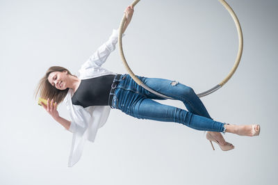 Low angle view of young woman exercising against sky