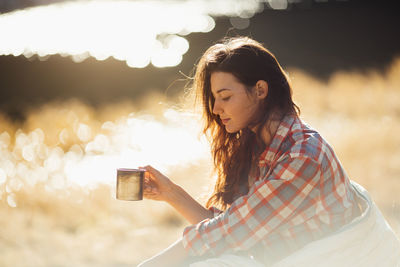 Portrait of woman holding camera while standing outdoors