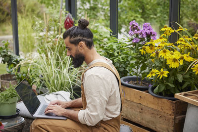 Man using laptop in greenhouse