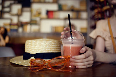 Midsection of woman drinking glass on table at restaurant