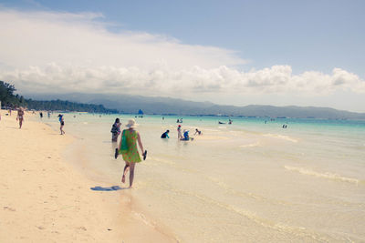 People at beach against sky