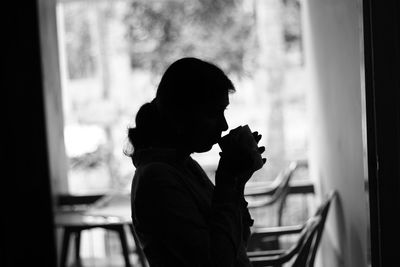 Side view of a silhouette man holding glass window