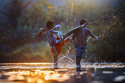 Side view of boys fighting in water