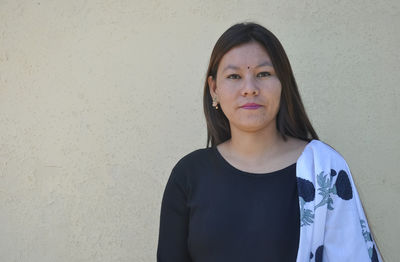 Portrait of woman standing against wall