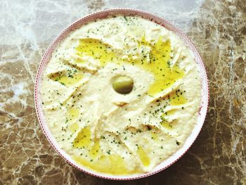 Directly above view of fresh olive in hummus served on table