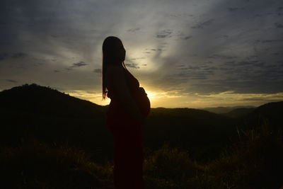 Silhouette person standing on field against sky during sunset