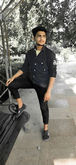 Portrait of young man standing against tree