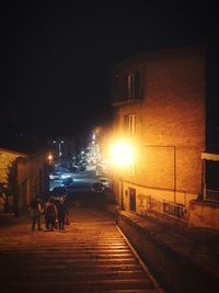People walking on illuminated street at night