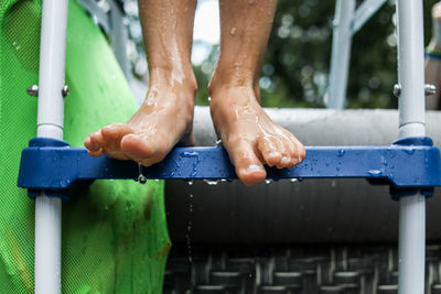 Close up of wet feet standing on pool ladder with water dripping off