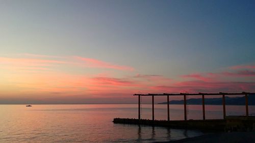 Pier over sea against sky during sunset