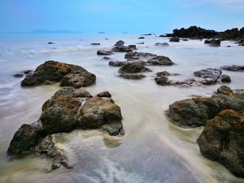 Rocks on sea shore against sky