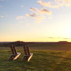 Scenic view of grassy field against sky at sunset