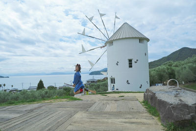 Rear view of woman standing on retaining wall against sky