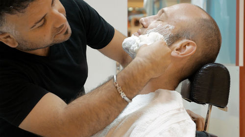 Barber shaving man at salon