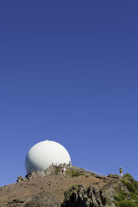 Low angle view of dome on hill against clear blue sky