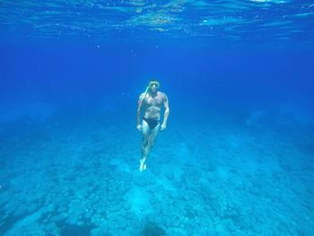 Full length of shirtless man swimming undersea