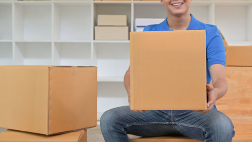 Full length of a young woman sitting in box