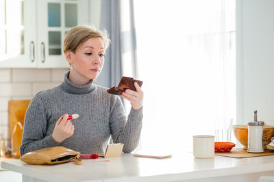 Mid adult woman doing make up while sitting at home