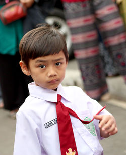 Portrait of boy standing in school uniform on road