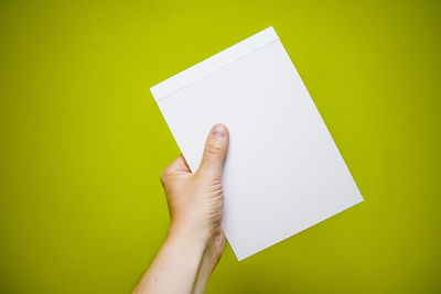 Close-up of hand holding paper against white background