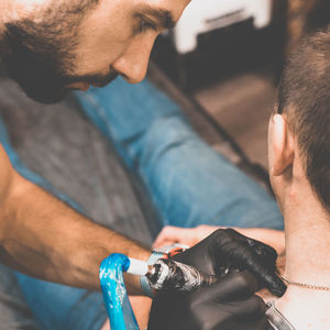 Midsection of man getting tattoo