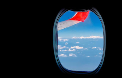 Reflection of clouds in sky seen through airplane window