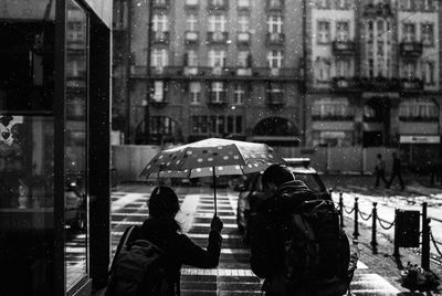 Rear view of people walking on footpath during rainy season