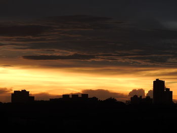 Silhouette city against sky during sunset