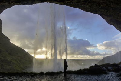 Silhouette man looking at sea against sky