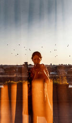 Portrait of a woman standing against glass window