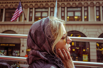 Close-up of thoughtful woman with hand on cheek against historic building