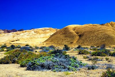 Scenic view of desert land against clear blue sky
