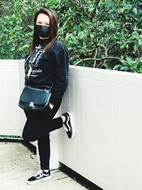 Portrait of young woman standing against wall