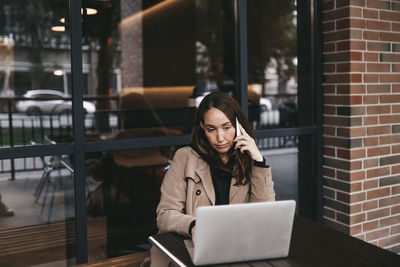 Young woman using phone while sitting on table