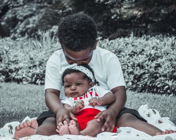 Father and daughter holding baby while standing outdoors