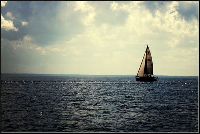 Boat in sea against cloudy sky