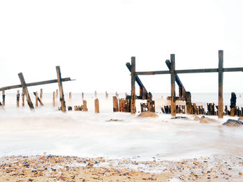 Wooden posts on beach against clear sky