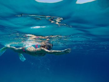 Woman scuba diving in blue sea