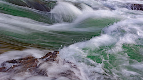 Scenic view of water rushing over rocks in a river