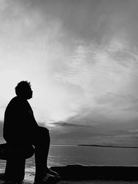 Silhouette man looking at sea against sky