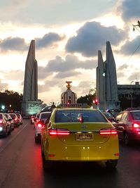 Cars on street against buildings in city during sunset